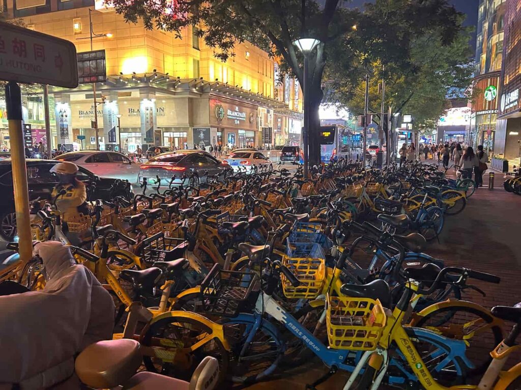 Długi rząd rowerów miejskich na ulicy w centrum Pekinu nocą